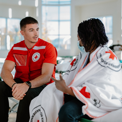 A Canadian Red Cross member assists an individual in need during an emergency, providing essential aid and support