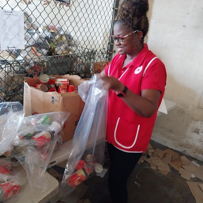 Une femme en veste rouge remplit un sac de fournitures