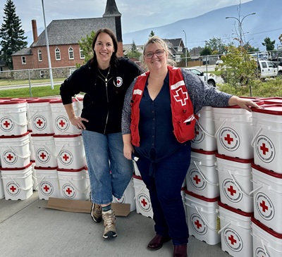 Deux femmes en tenue de la Croix-Rouge canadienne devant des bacs avec l'emblème de la Croix-Rouge