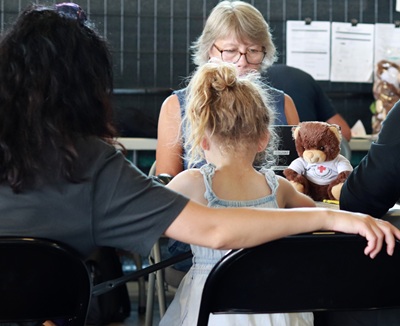 Un groupe de personnes dans une salle avec un ourson de la Croix-Rouge