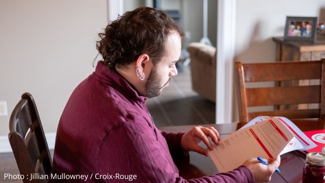 Une personne assise à une table lisant un document sur le plan d'urgence de la Croix-Rouge.