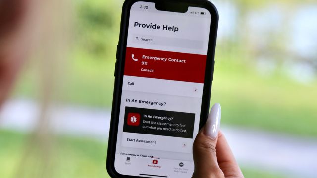 A person holding a cell phone, with the Red Cross first aid app displaying on the screen.