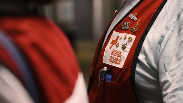 Personne portant un gilet de la Croix-Rouge avec des épingles.