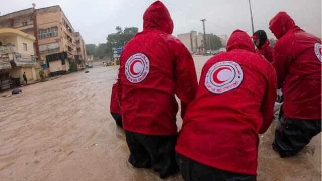 Cinq personnes aident l’équipe du Croissant-Rouge libyen lors des inondations. 