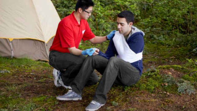 A Wilderness and Remote First Aid Instructor has finished placing a regular sling on an arm injury.