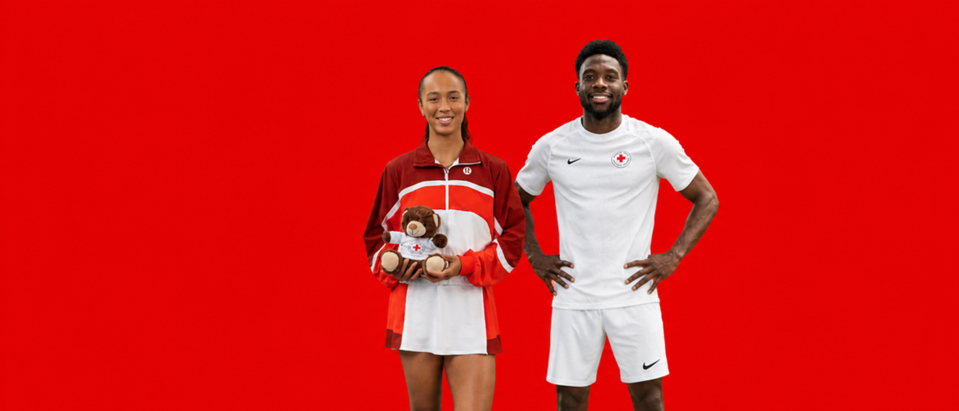 Alphonso Davies et Leylah Fernandez se tiennent côte à côte : à gauche, Leylah tient un ourson de la Croix-Rouge ; à droite, Alphonso porte un t-shirt de la Croix-Rouge.