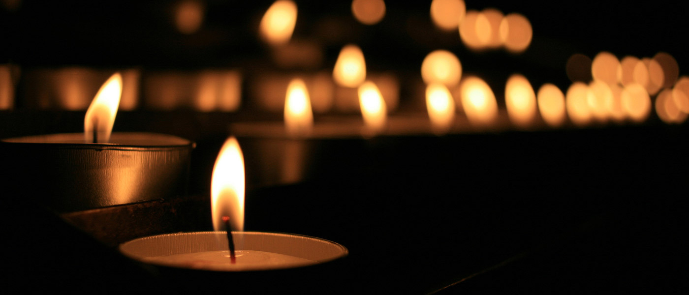 Tealight candles burn in darkness.