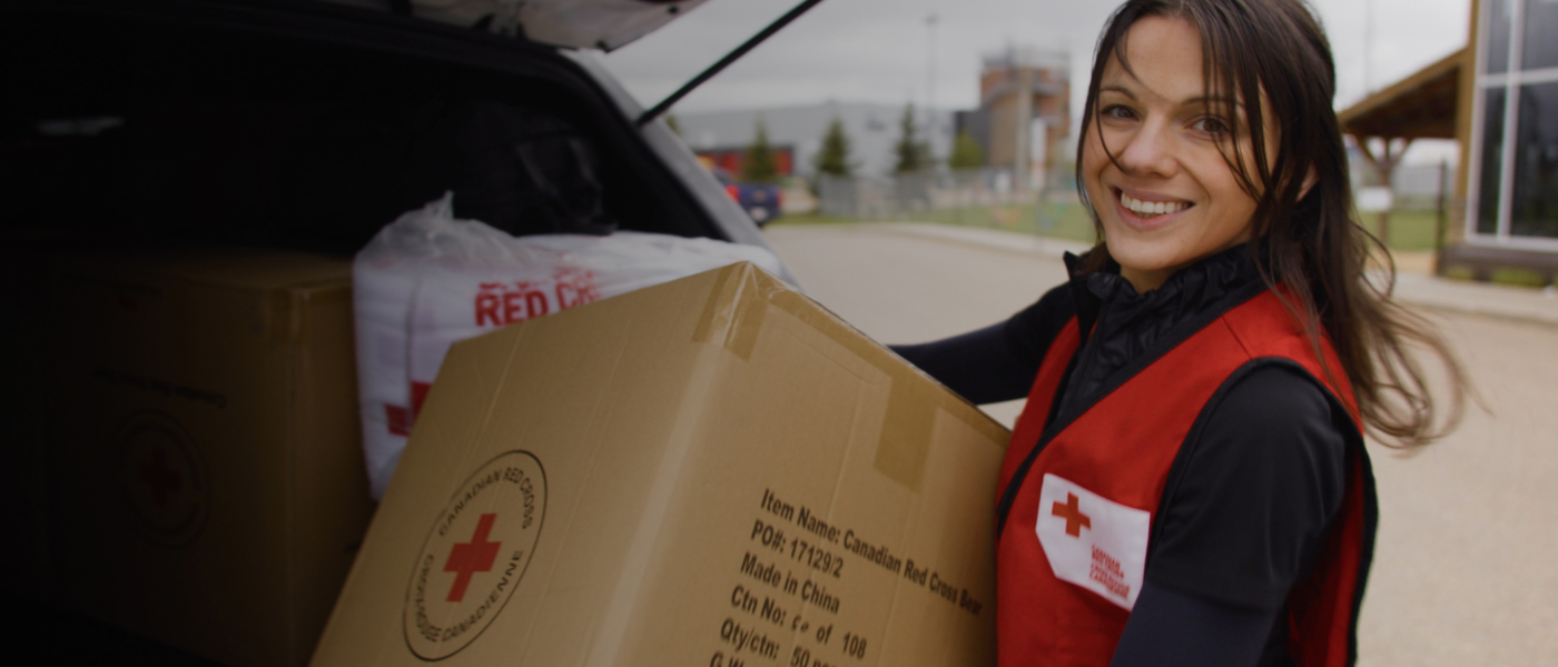 Une employ&#xE9;e de la Croix-Rouge transporte une bo&#xEE;te de fournitures en souriant.