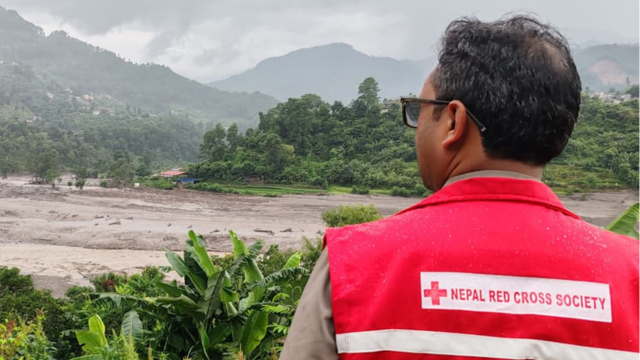 A member of the Nepal Red Cross overlooking a flooded landscape.