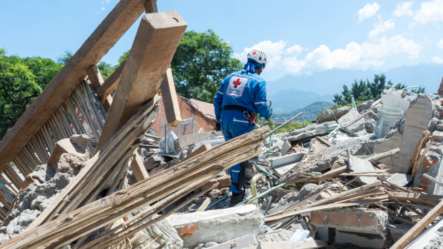 Red Cross responder assesses earthquake damage amid debris in Colombia.