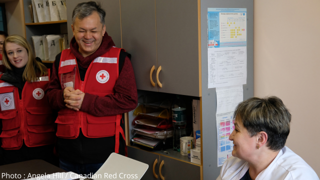 An image of a Canadian Red Cross staff carrying a box