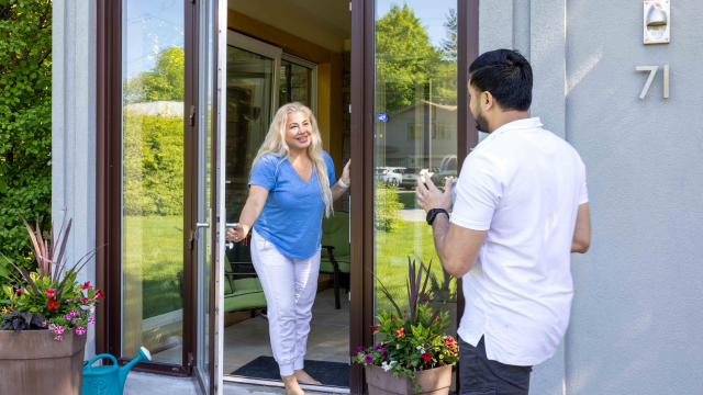 Une personne accueille une autre personne à sa porte d'entrée.