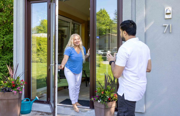A person greets another person at their front door.