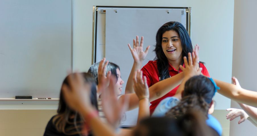 Un membre du personnel de la Croix-Rouge applaudit un groupe d'élèves dans une salle de classe.