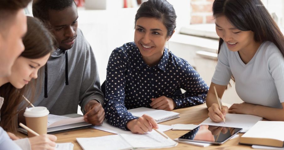 A group of people gather around a table taking notes