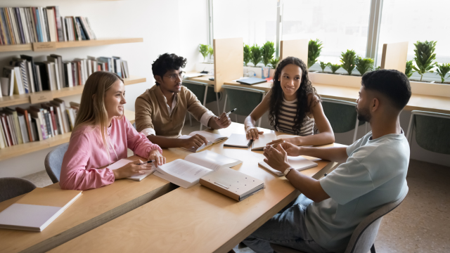 A group of people gather around a table taking notes