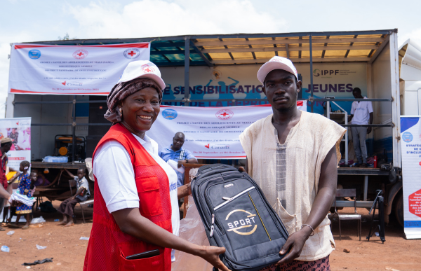  Red Crosser with a community recipient holding a   
backpack.