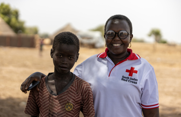 Une coordonnatrice de projet de la Croix-Rouge du Soudan du Sud pose avec un jeune membre de la communauté.