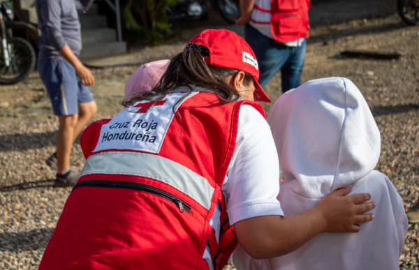Un membre de la Croix-Rouge du Honduras place sa main sur le dos d’un jeune enfant.