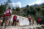 A group of people wearing Red Cross vests gathered around tents