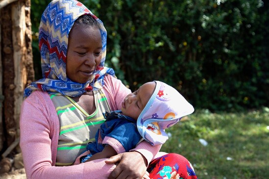 Woman in colourful clothing holds baby with a loving gaze