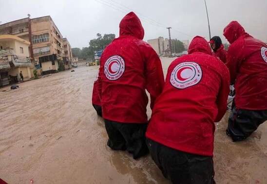 A group of people in red jackets standing in flood water