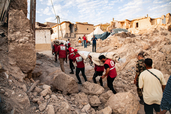 A group of people in red vests carrying a large bag on their backs