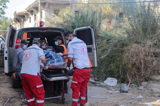 A group of people placing a person on a stretcher into a van