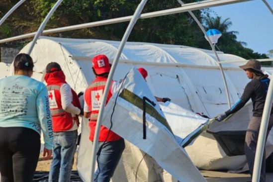 Des personnes portant des dossards de la Croix-Rouge montent une tente