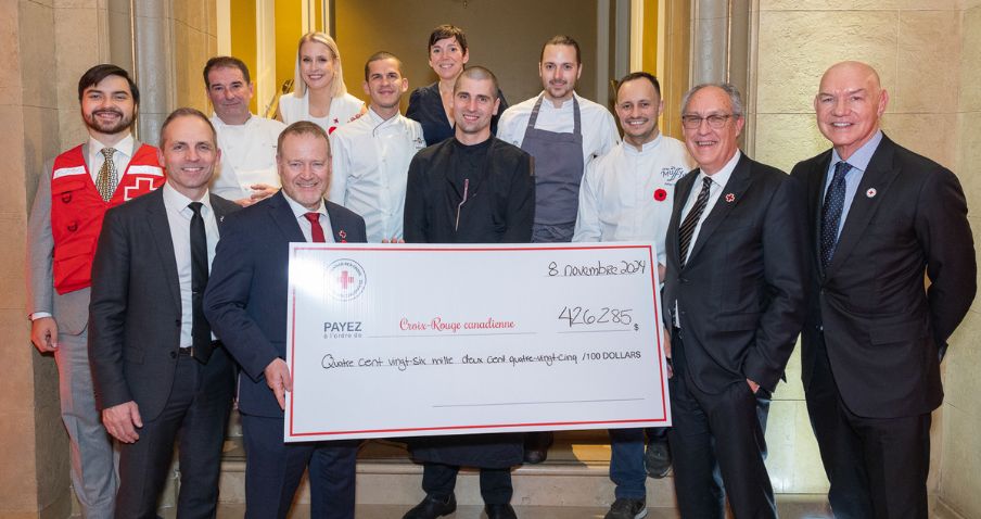 A group of people gather for a photo, holding a large Red Cross paper cheque