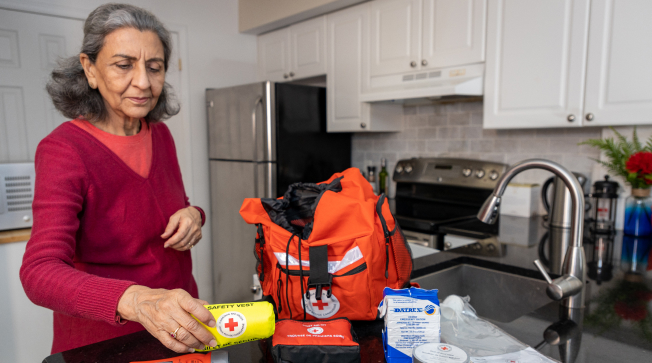 Une femme d’un certain âge assemble un sac prêt-à-emporter dans sa cuisine.