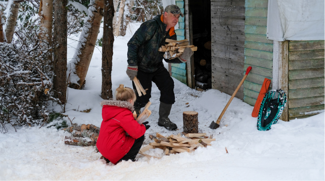 A man gathers wood with his daughter outside in the winter preparing in case of emergencies.