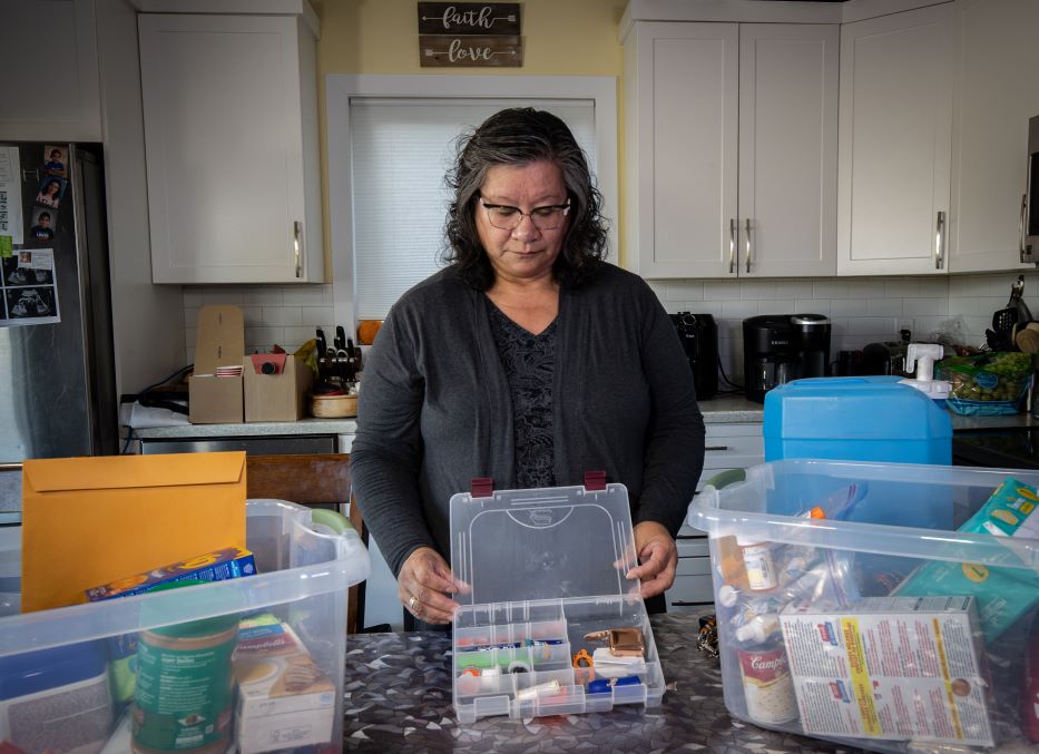 An older woman displays her beading kit, which is going into her emergency kit.