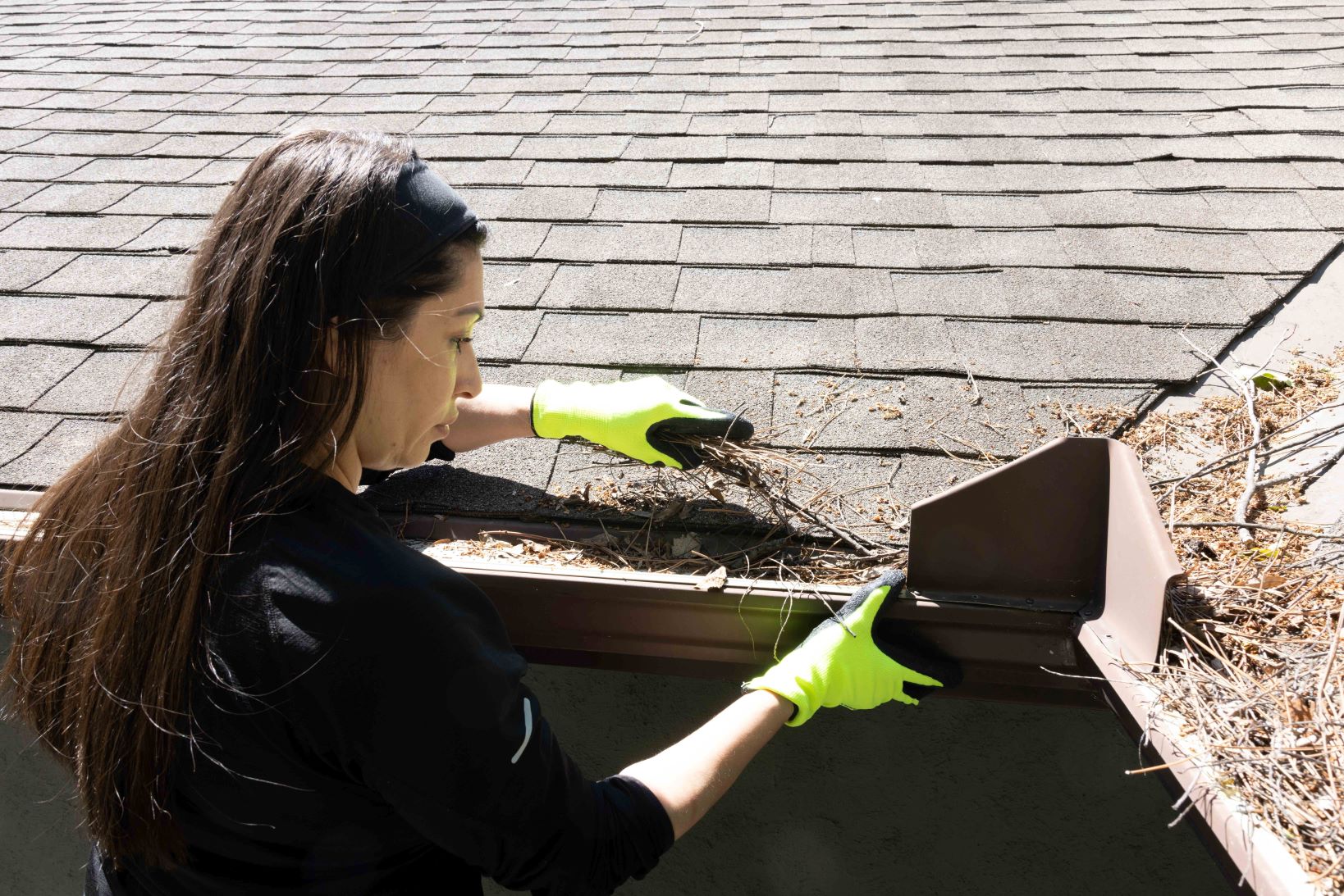 A woman cleans the gutters to remove debris that could be a fire hazard. (Credit John Falcon)