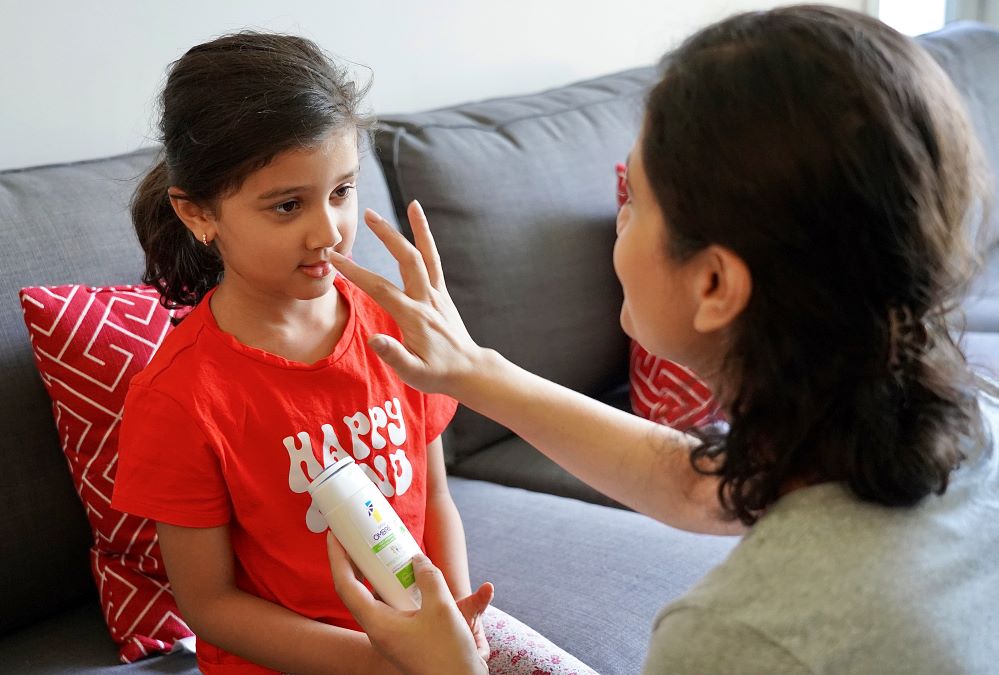 Un adulte applique de la crème solaire sur le visage d’un enfant.