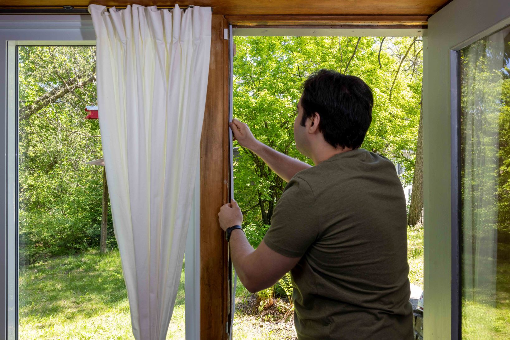 A person adds weather stripping to their window to help with heat and cold fluctuations. (Credit John Falcon)