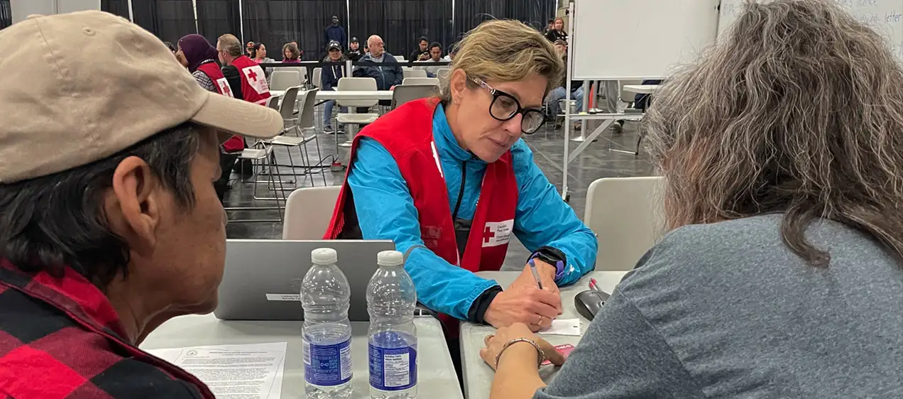 Canadian Red Cross volunteer Linda Aldridge assists residents assists two people evacuated from the Northwest Territories with lodging support in Edmonton.