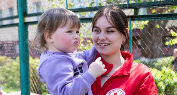 redcross volunteer holds child