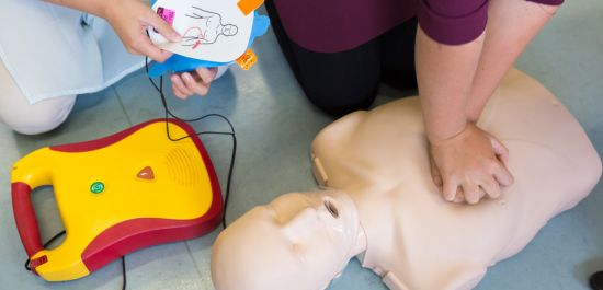 Deux personnes utilisant un défibrillateur sur un mannequin de premiers soins.