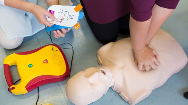 Deux personnes utilisant un défibrillateur sur un mannequin de premiers soins.