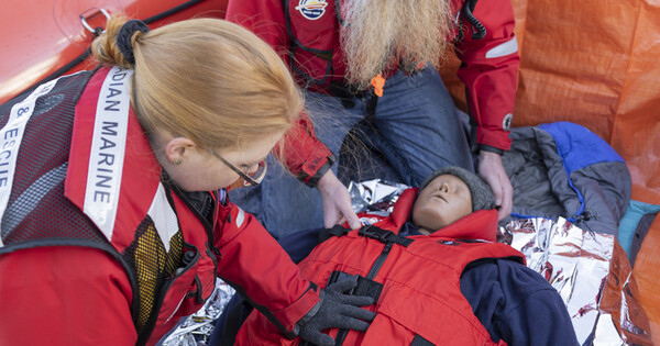 Deux membres de l’équipage d’un bateau s’entraînent à envelopper une personne souffrant d’hypothermie à l’aide d’un mannequin.
