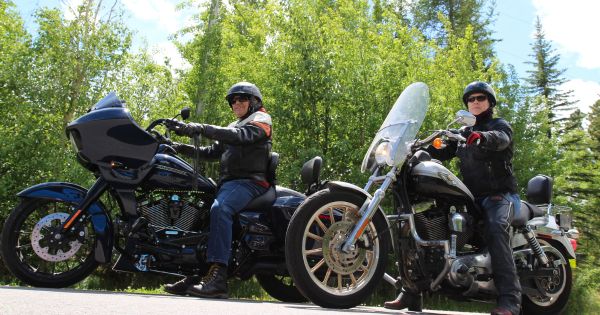 Deux personnes portant l’équipement nécessaire pour faire de la moto sont assises sur des motocyclettes.