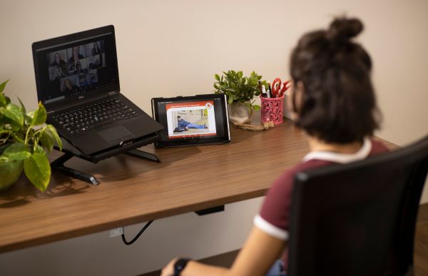 Une personne assise à un bureau regarde attentivement l’écran de son ordinateur.