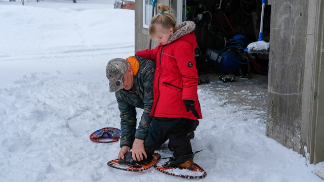 Adult helping a child put on winter clothing to stay warm and safe in cold weather.