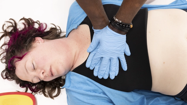 Personne effectuant des compressions thoraciques sur une autre personne allongée sur le sol, pratiquant la RCP dans une situation d'urgence