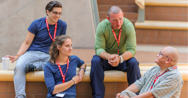 Four people sitting in a circle having a discussion about psychological aid, appearing engaged and supportive.