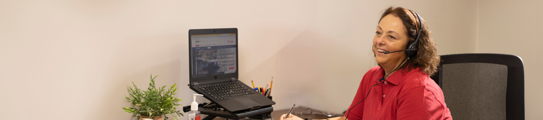 Une agent du service d'assistance porte un casque audio et sourit.
