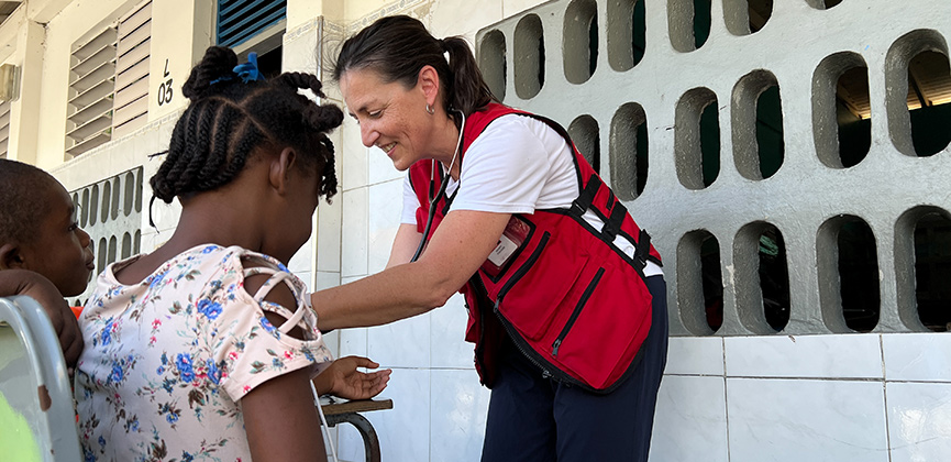 Une femme portant un gilet de la Croix-Rouge aide un enfant.