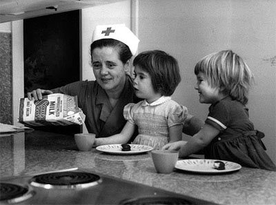 Une infirmière de la Croix-Rouge nourrissant deux enfants pendant la Première Guerre mondiale