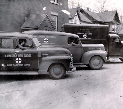 Trois voitures de la Croix-Rouge alignées dans la rue pendant la Seconde Guerre mondiale 